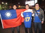 Kuan-sseng Wu (center), 23, a student from Taiwan, shows off his Jeremy Lin jersey while posing alongside the Taiwanese flag. Photo by Louie Lazar.