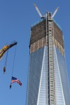 A flag is suspended from a crane next to 1 World Trade Center, the building formerly known as the Freedom Tower. by Alyana Alfaro