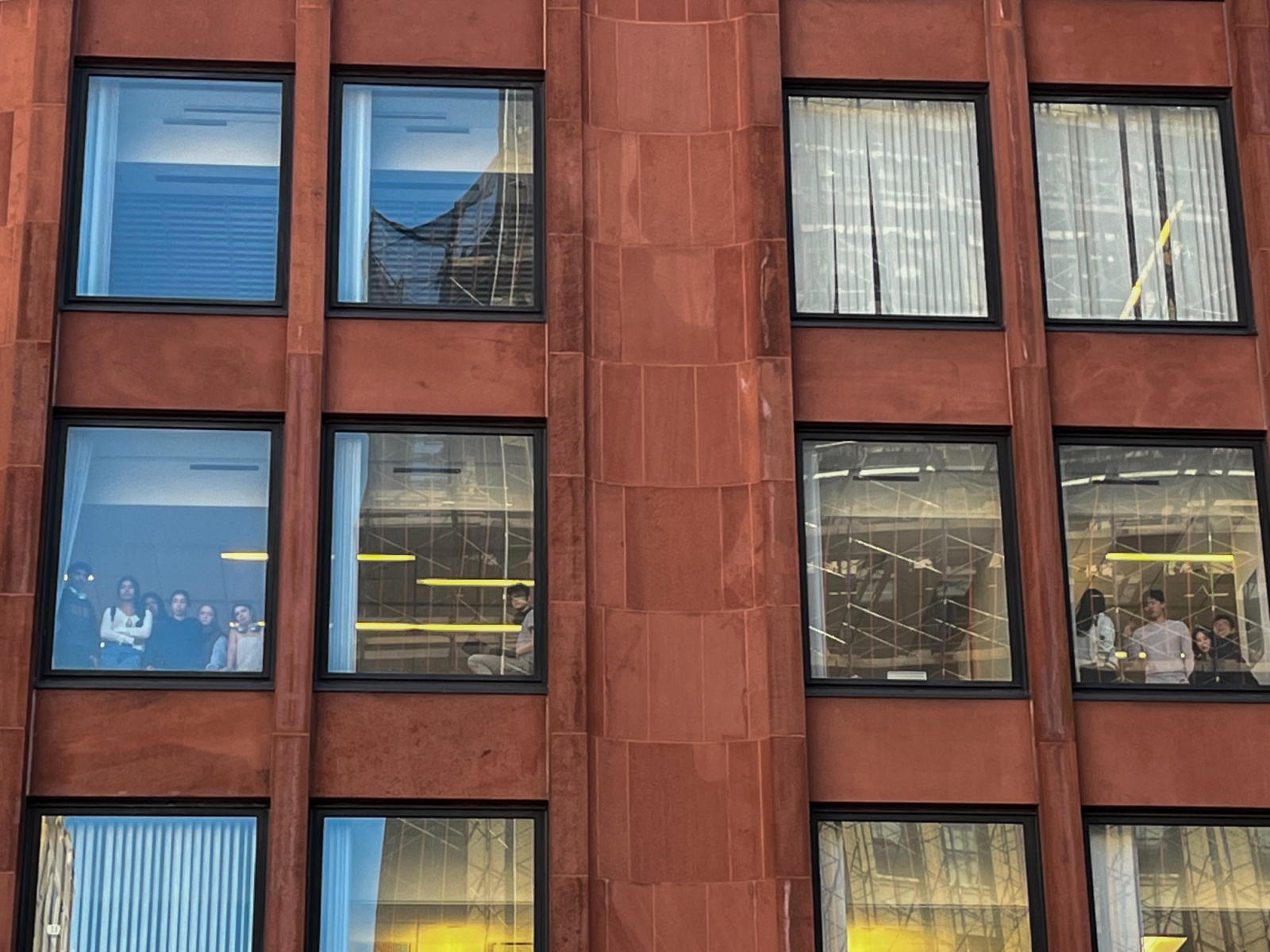 Students inside the NYU Stern School of Business watched from indoors as people occupied Gould Plaza on Monday. (Photography by Ryan Schwach)