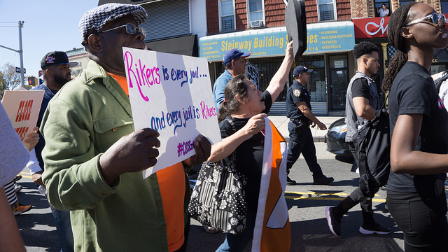 Protestors hold handmade signs draw attention to the faulty prison system at Rikers Island.. Hundreds of people of color marched yesterday to protest the condition at the jail. Rikers Island. Photo by Sophie Herbut.